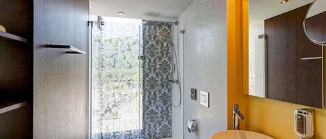 Un baño moderno con mampara de vidrio, inodoro y un lavamanos grande.