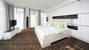 Una habitación de hotel moderna con una cama grande, un televisor y un armario.