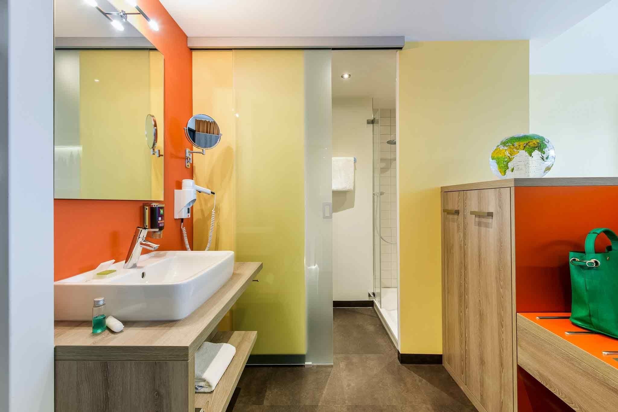 A modern bathroom with a large mirror, a sink, and a shower.
