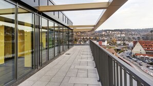 Un balcón con vistas a un paisaje urbano, que incluye edificios modernos y un cielo despejado.