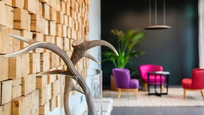 Un interior moderno con una pared de madera, un florero de vidrio con astas y una zona de estar con sillas y una planta.