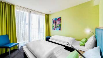 Une chambre d’hôtel avec un lit, une chaise bleue, une petite table et un tableau accroché au mur.