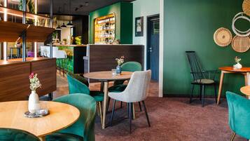 A restaurant with green walls, wooden furniture, and a bar area.