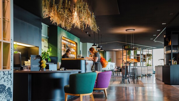 Un moderno vestíbulo de hotel con un mostrador de recepción, zona de estar y un bar.