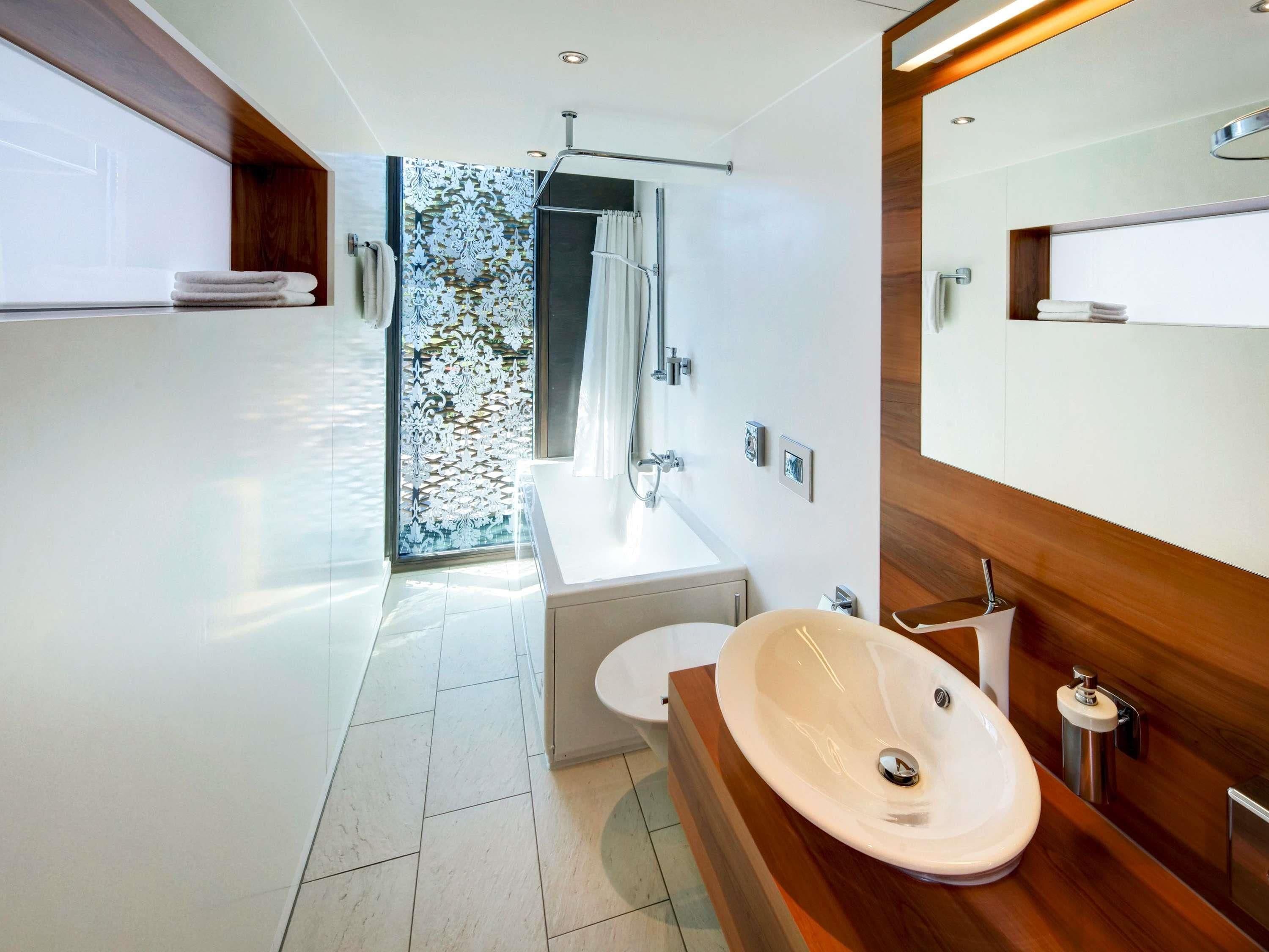 A modern bathroom with a large mirror, a sink, and a shower.