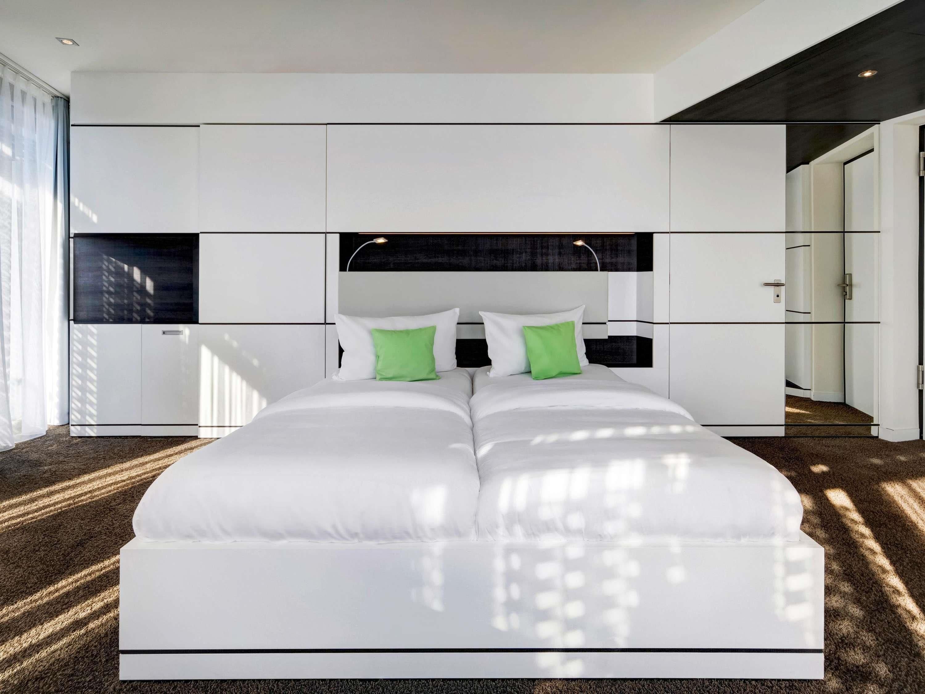 Un dormitorio moderno con una cama grande, decoración en blanco y negro y vista a un edificio.