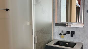 A modern bathroom with a built-in sink, a mirror with integrated lighting, and a toilet.