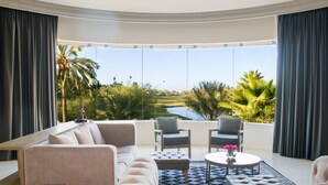 A modern living room with a large sofa, two armchairs, a coffee table, and a view of a golf course. - Azul Talavera Country Club (Torreón)