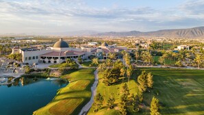 A golf course with a large building featuring a dome, surrounded by palm trees and a body of water. - Azul Talavera Country Club (Torreón)
