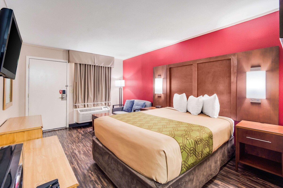 Une chambre d’hôtel comprenant un lit, des tables de chevet, une télévision, un bureau et une armoire.