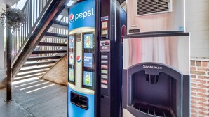 Una máquina expendedora con el logotipo de Pepsi, un equipo de aire acondicionado marca Scotsman y una escalera al fondo.