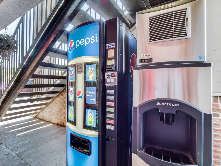 Una máquina expendedora con el logotipo de Pepsi, un equipo de aire acondicionado marca Scotsman y una escalera al fondo.