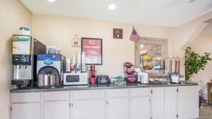 Un área de cocina con cafetera, microondas, tostadora y refrigerador.