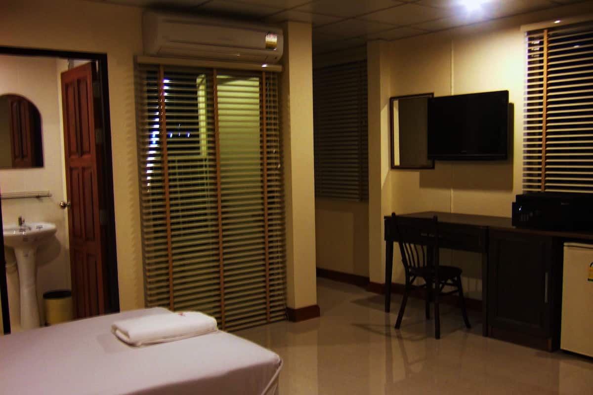 A hotel room with a bed, a desk, a television, and a sink.
