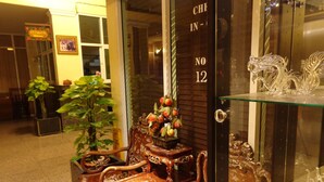 A traditional wooden chair with intricate carvings, a glass display case with decorative items, and a door with a number. - Lodge 61 Bed & Breakfast (Bangkok)