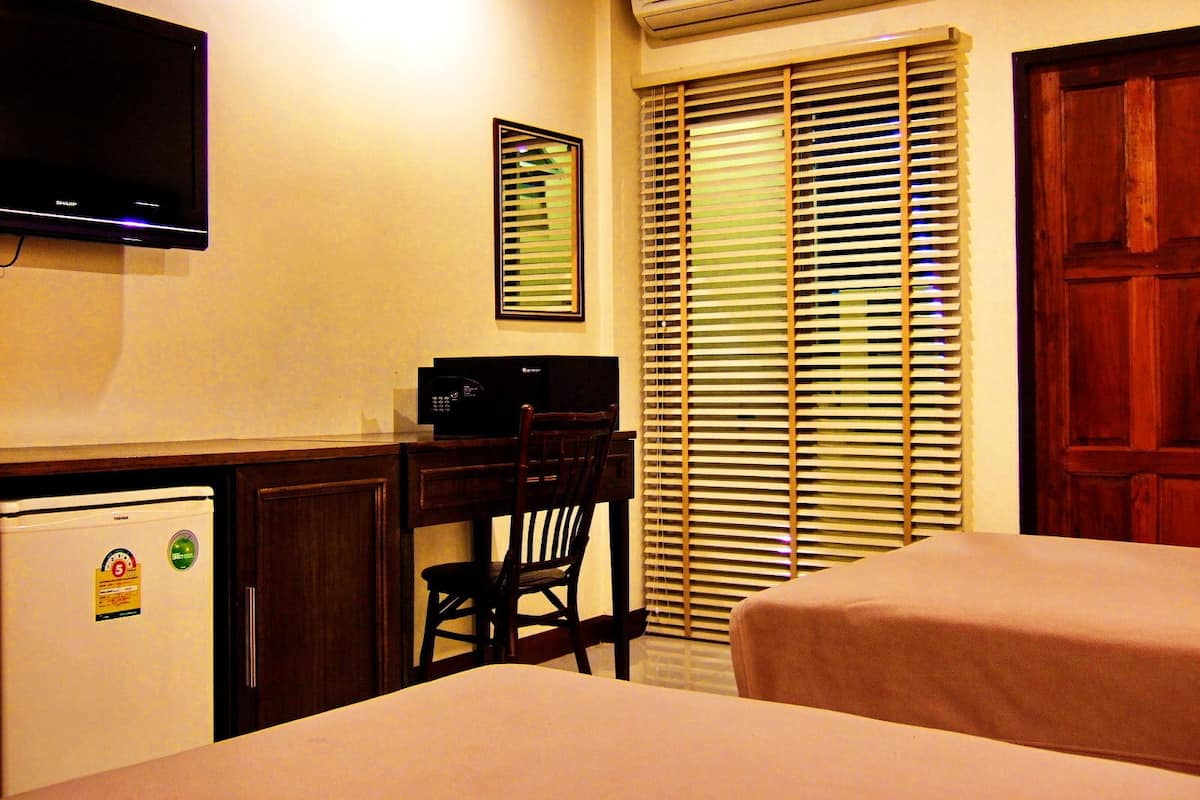 A hotel room with a desk, a chair, a bed, and a television.