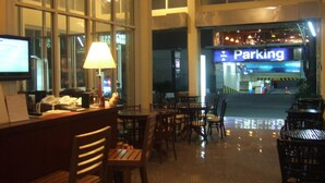 A hotel lobby with a reception desk, chairs, and a large window overlooking a parking area. - Lodge 61 Bed & Breakfast (Bangkok)
