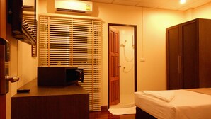 A hotel room with a bed, a desk, a wardrobe, and a shower area. - Lodge 61 Bed & Breakfast (Bangkok)