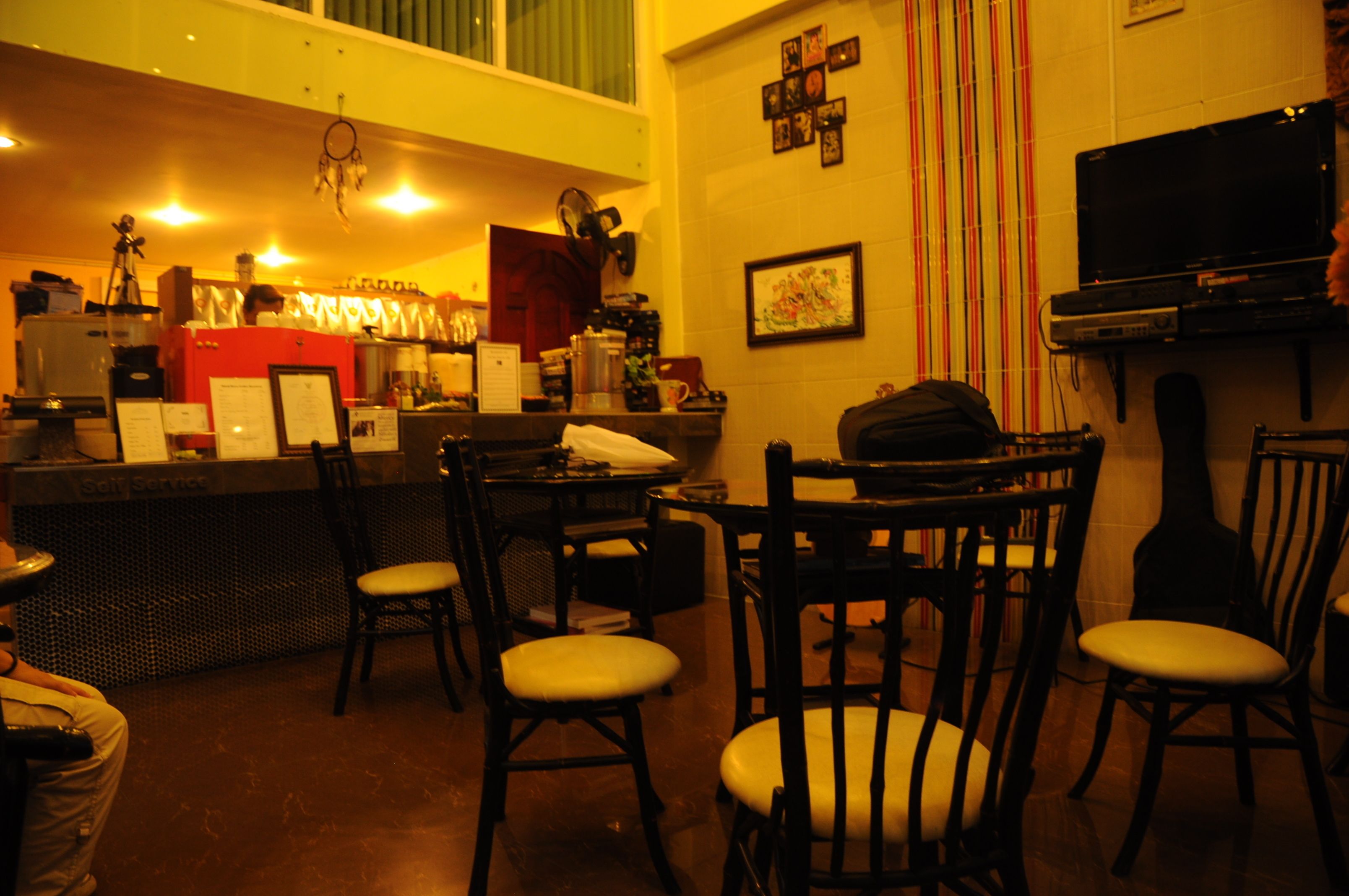 A bar area with wooden chairs, a television, and various bar equipment.