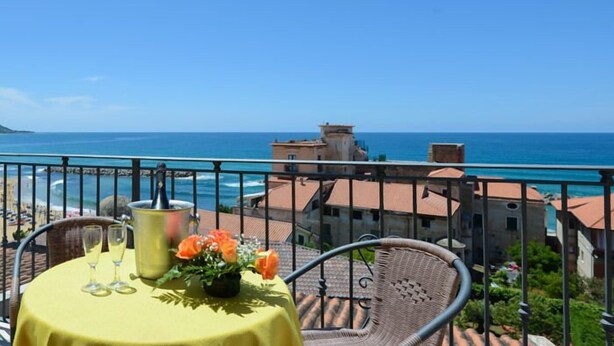 A balcony with a table set for two, overlooking a coastal view. - La Pergola (Castellabate)
