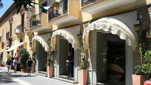 A row of boutique hotels with arched awnings and large potted plants. - La Pergola (Castellabate)