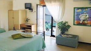 A hotel room with a bed, a desk, a chair, a television, a window with curtains, and a plant. - La Pergola (Castellabate)