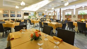 A spacious dining area with multiple tables set for service, featuring a consistent yellow tablecloth theme and modern lighting fixtures. - La Pergola (Castellabate)