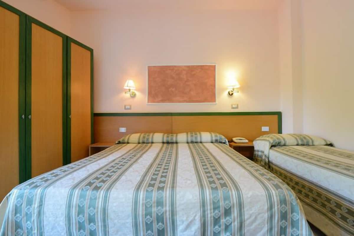 Ein Hotelzimmer mit zwei Betten, einem Holzschrank und zwei Wandleuchten.