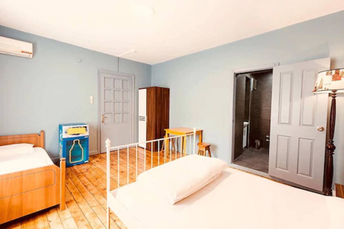 Un dormitorio con dos camas, un armario, un escritorio y una puerta que da a un baño.