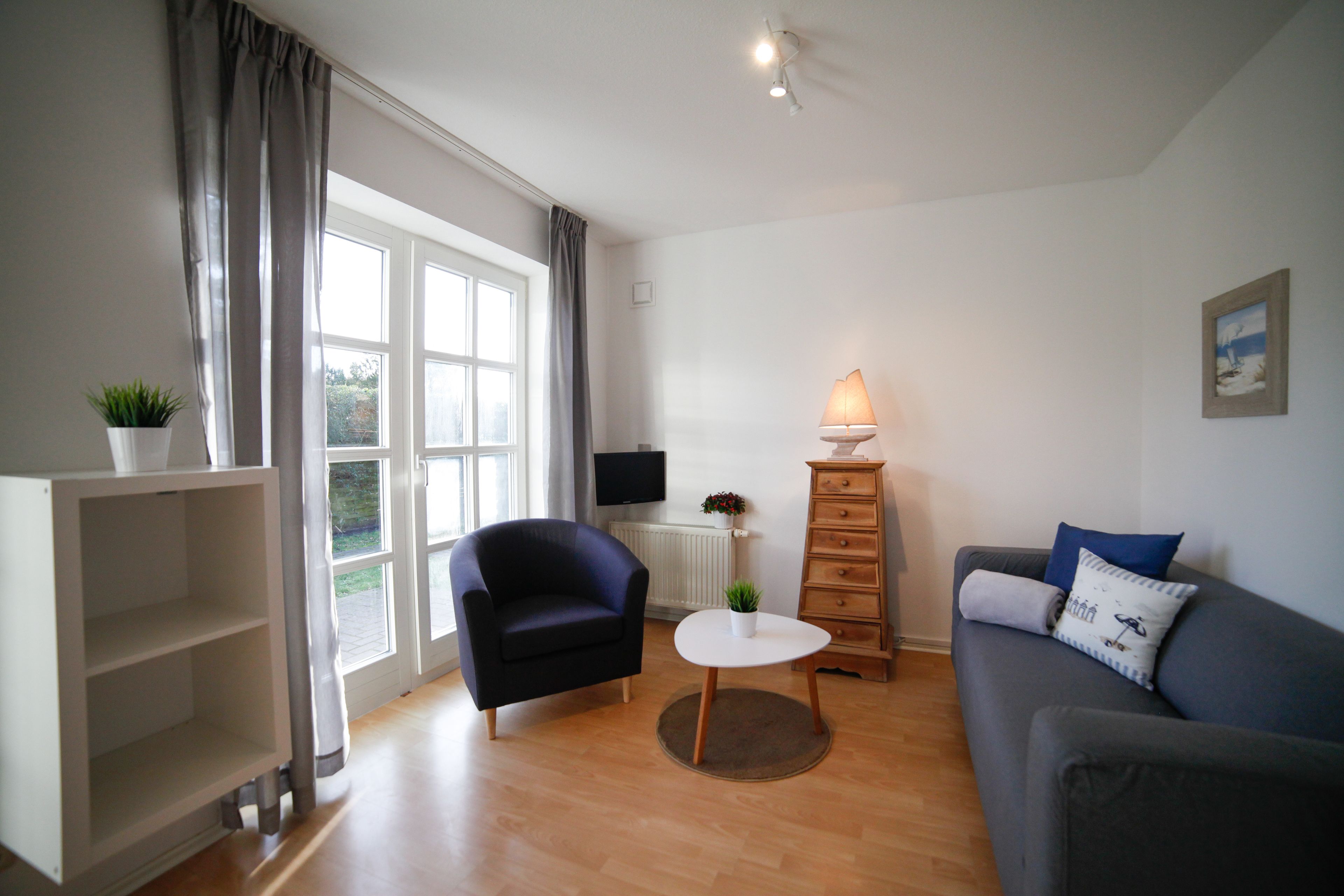 A living room with a sofa, armchair, and a small table with a lamp.