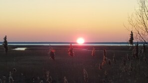 A sunset over a flat landscape with sparse vegetation and a distant horizon. - Captain Pahlen Ferienanlage (Zingst)