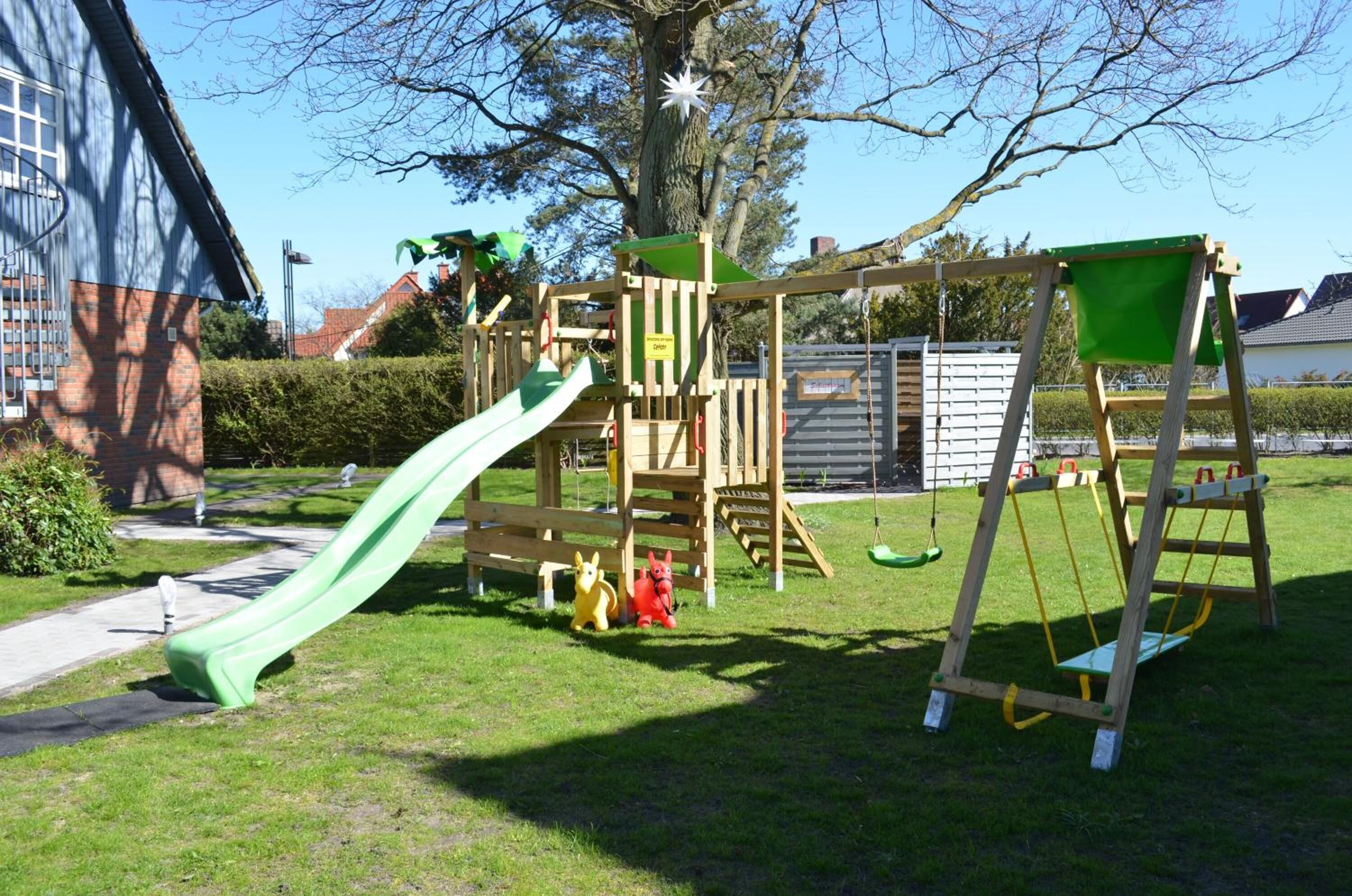 Ein Spielplatz mit Rutsche, Klettergerüsten und Schaukeln.