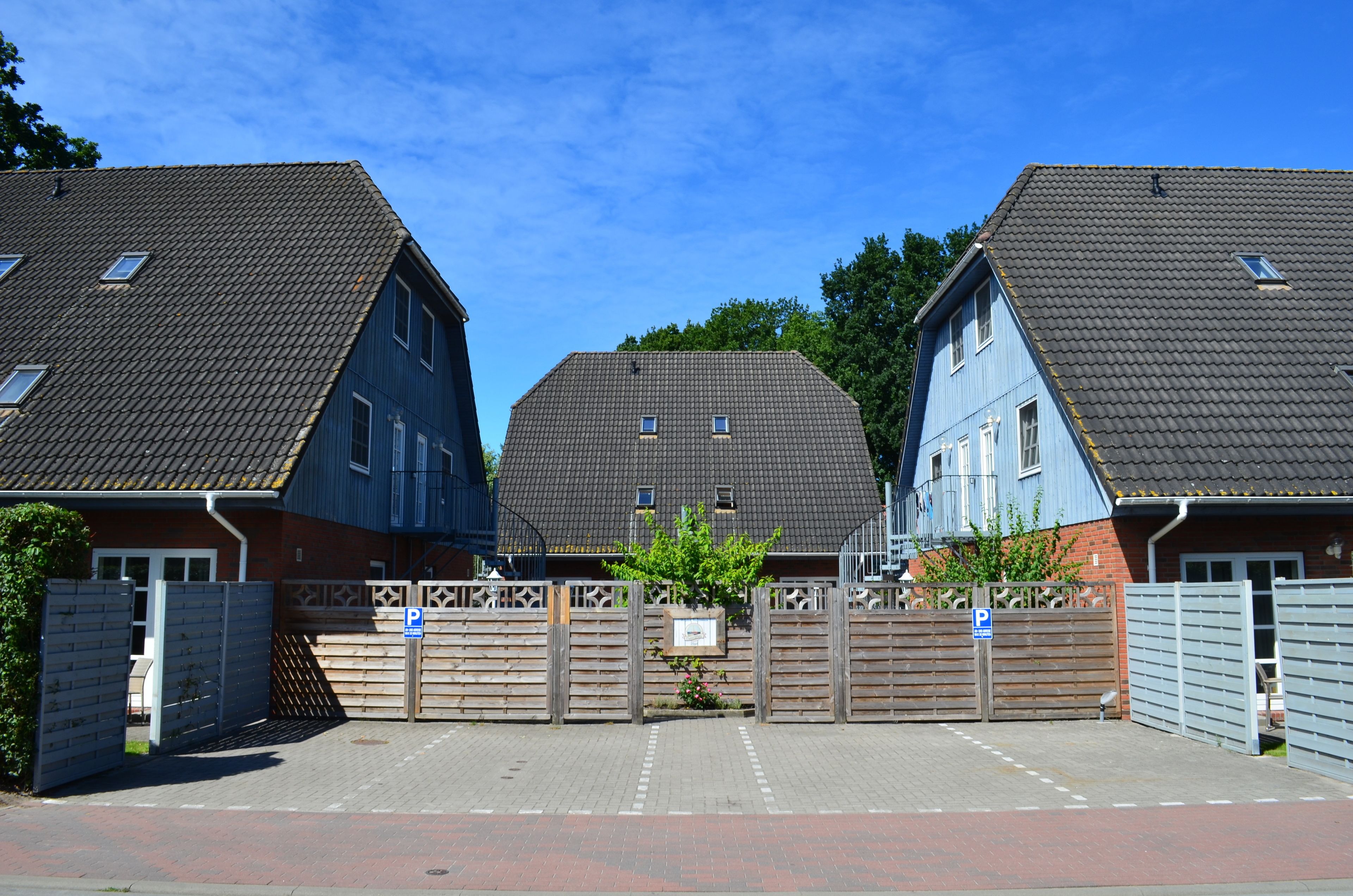 A residential area with three houses, each with a distinct roof style and a gated entrance.