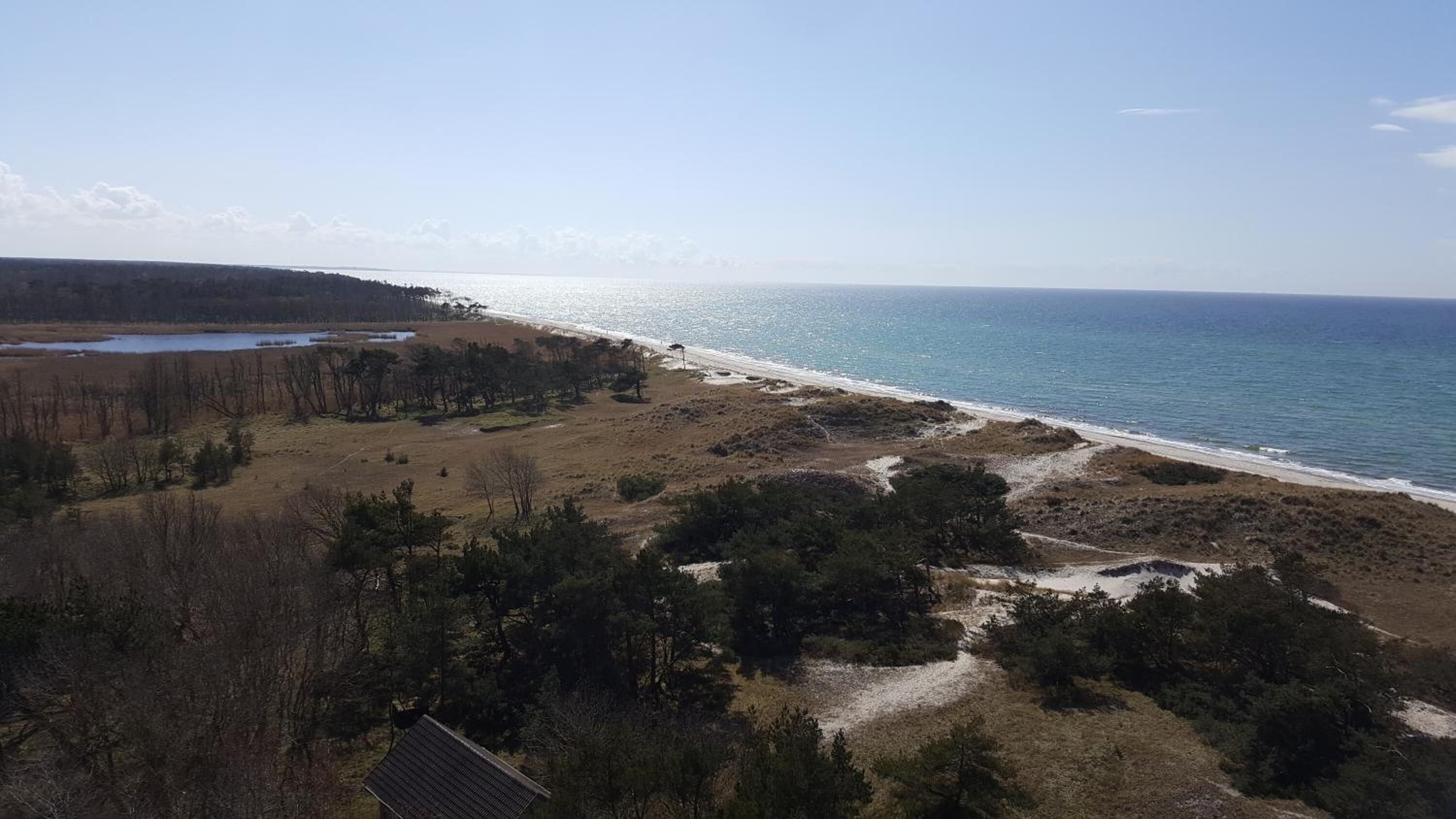 A coastal landscape with a beach, a small body of water, and sparse vegetation.