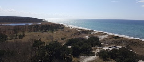 A coastal landscape with a beach, a small body of water, and sparse vegetation.