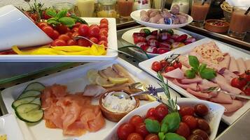 Un bufé con diversos alimentos, entre ellos salmón ahumado, tomates cherry y diferentes tipos de queso.