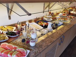 Buffet variado com frutas, iogurte e sanduíches.