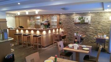 A restaurant with a bar area, wooden furniture, and a stone wall.