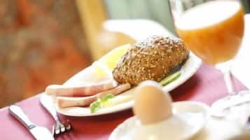 Ein Frühstückstisch mit Essen, Orangensaft und einer Tasse.
