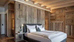 A wooden-paneled bedroom with a bed, bedside tables, and a nightstand. - Almdorf Almlust (Flachau)