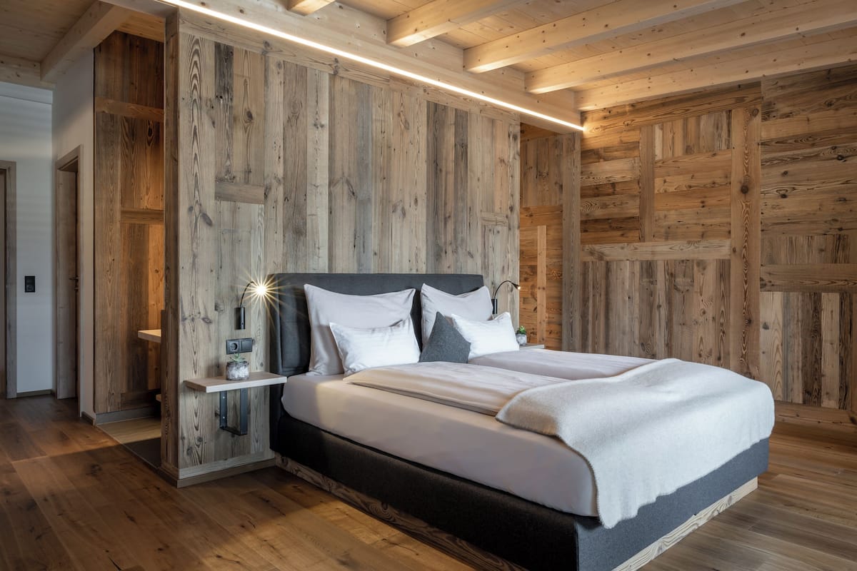 A wooden-paneled bedroom with a bed, bedside tables, and a nightstand.