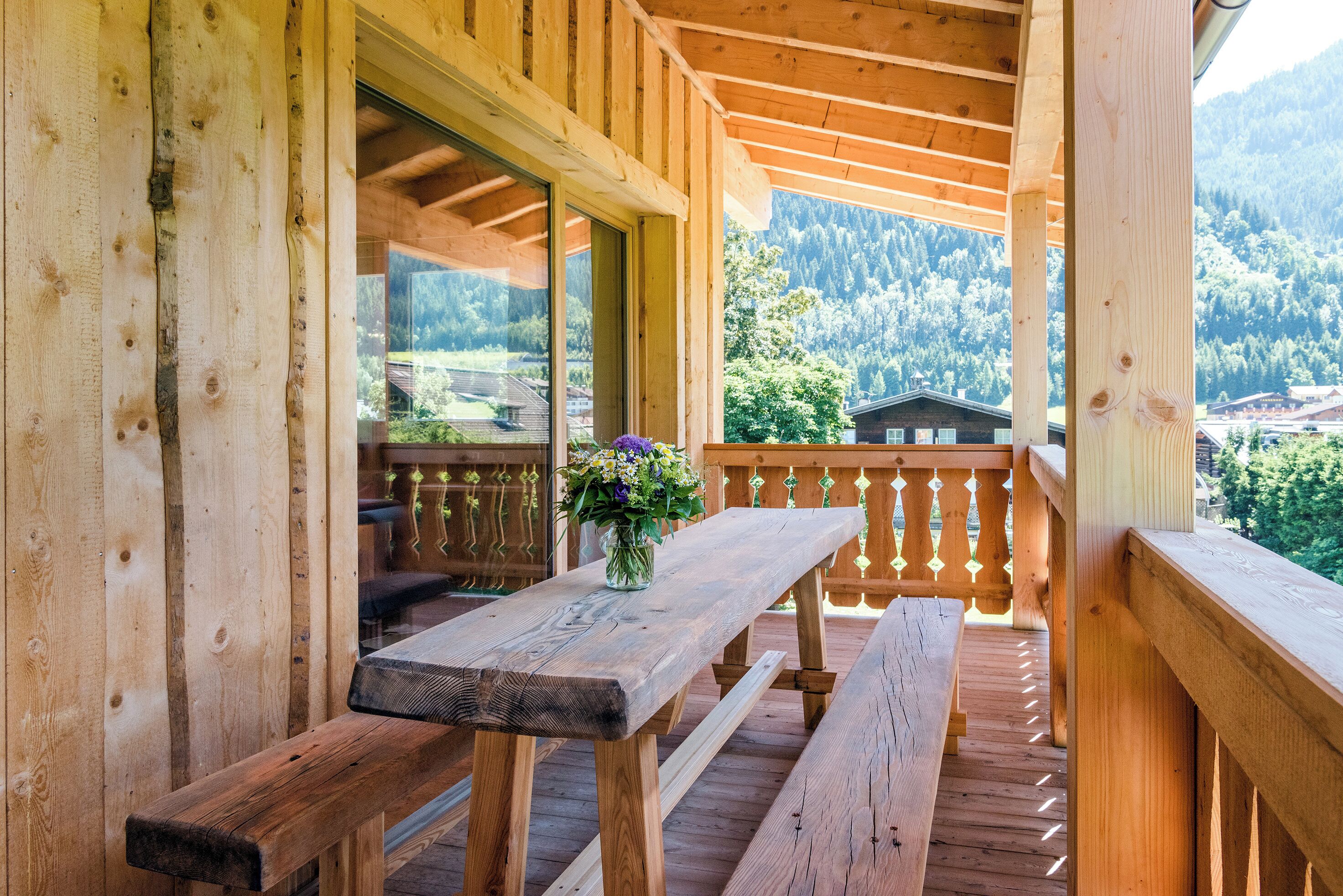 A wooden deck with a table and benches, overlooking a mountainous landscape.