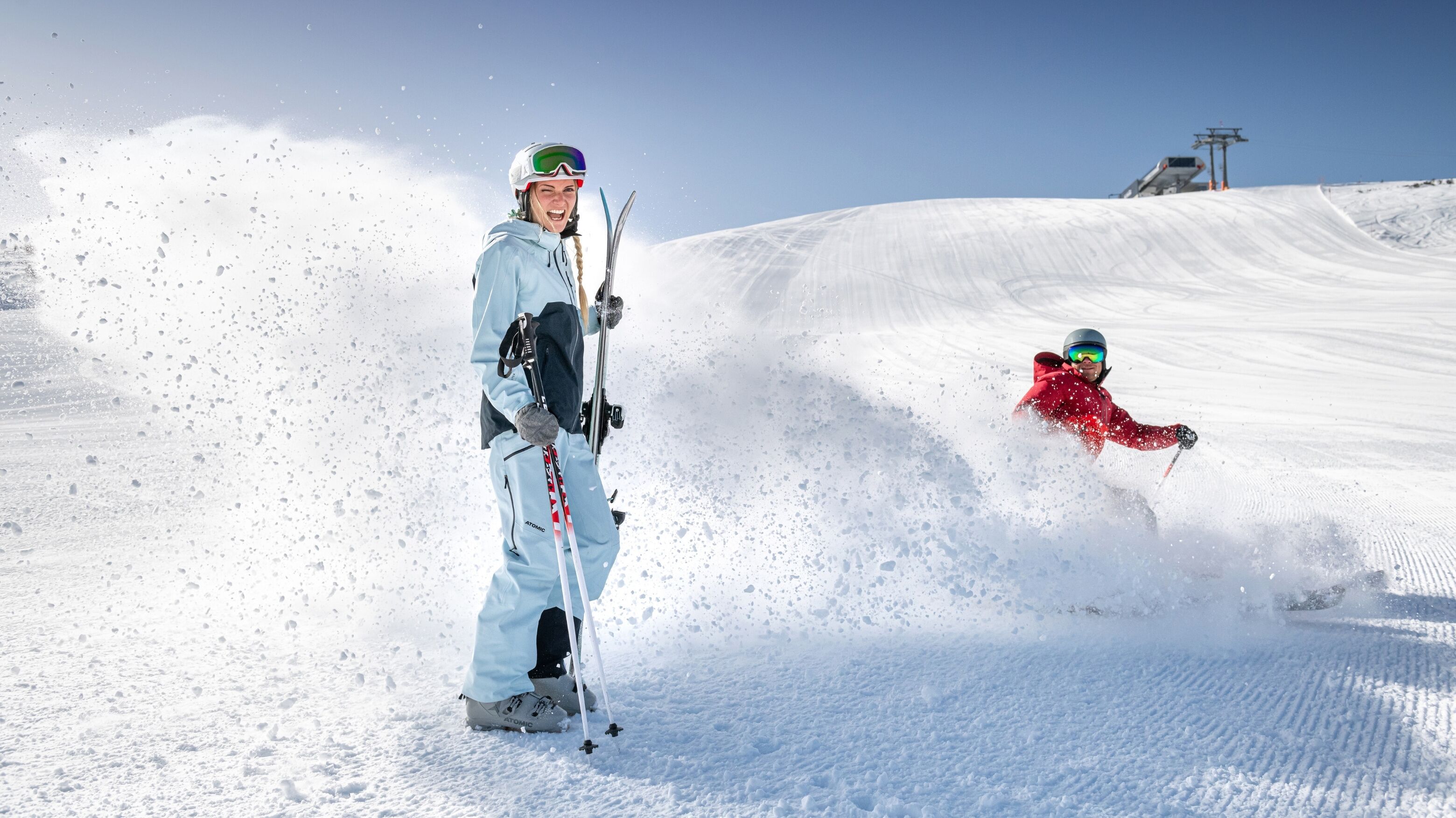A snowy landscape with a ski slope, a ski lift, and a person in a red jacket skiing.