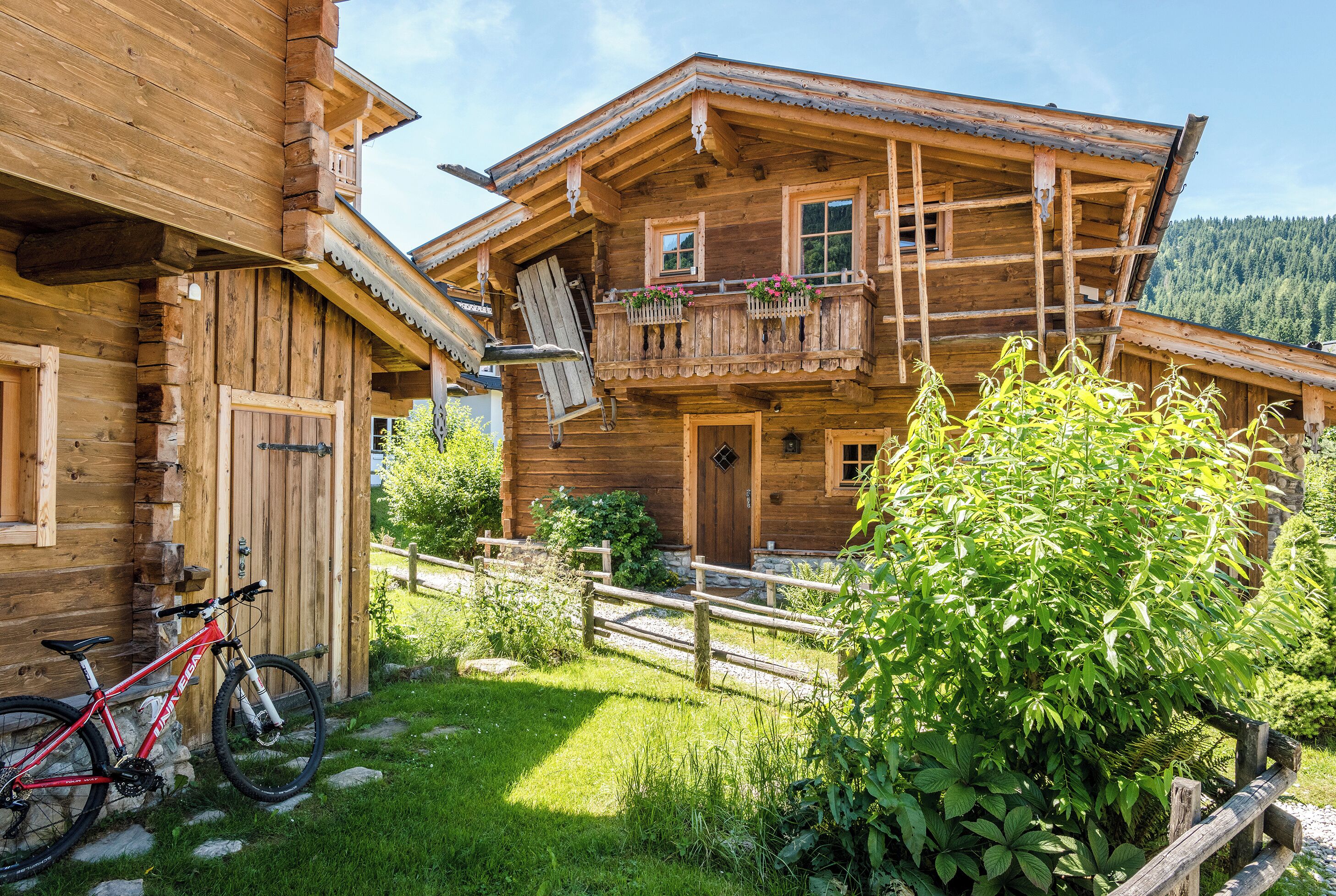 A wooden chalet with a balcony, a bicycle, and a garden.