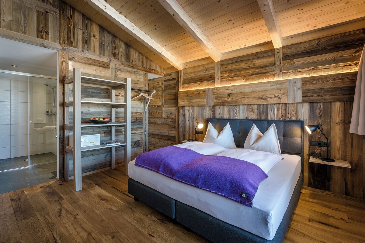 Quarto com painéis de madeira, uma cama, guarda-roupa embutido e área de chuveiro.