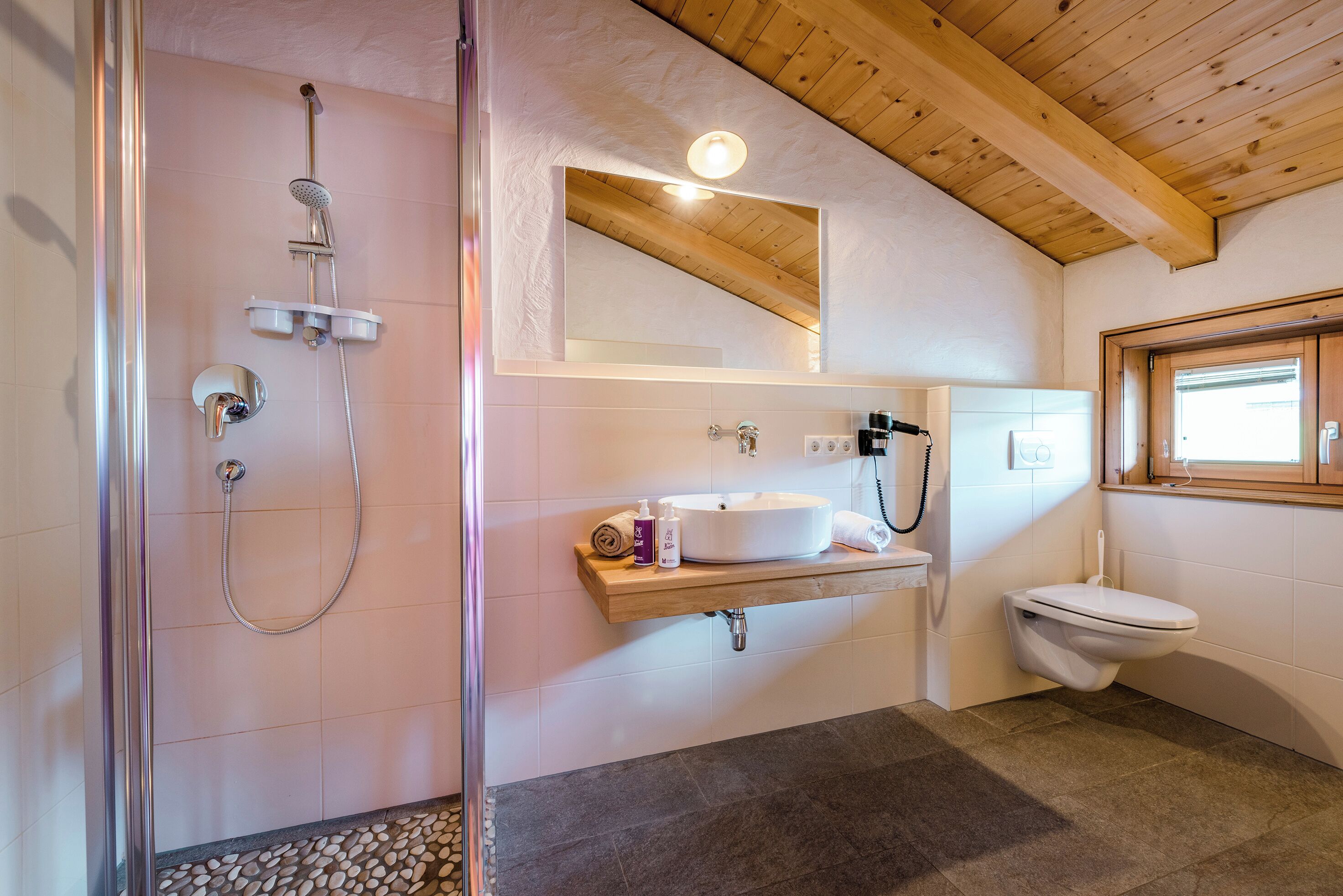 Une salle de bain avec douche, toilettes, lavabo et un plafond en bois.