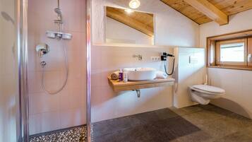 Une salle de bain avec douche, toilettes, lavabo et un plafond en bois.