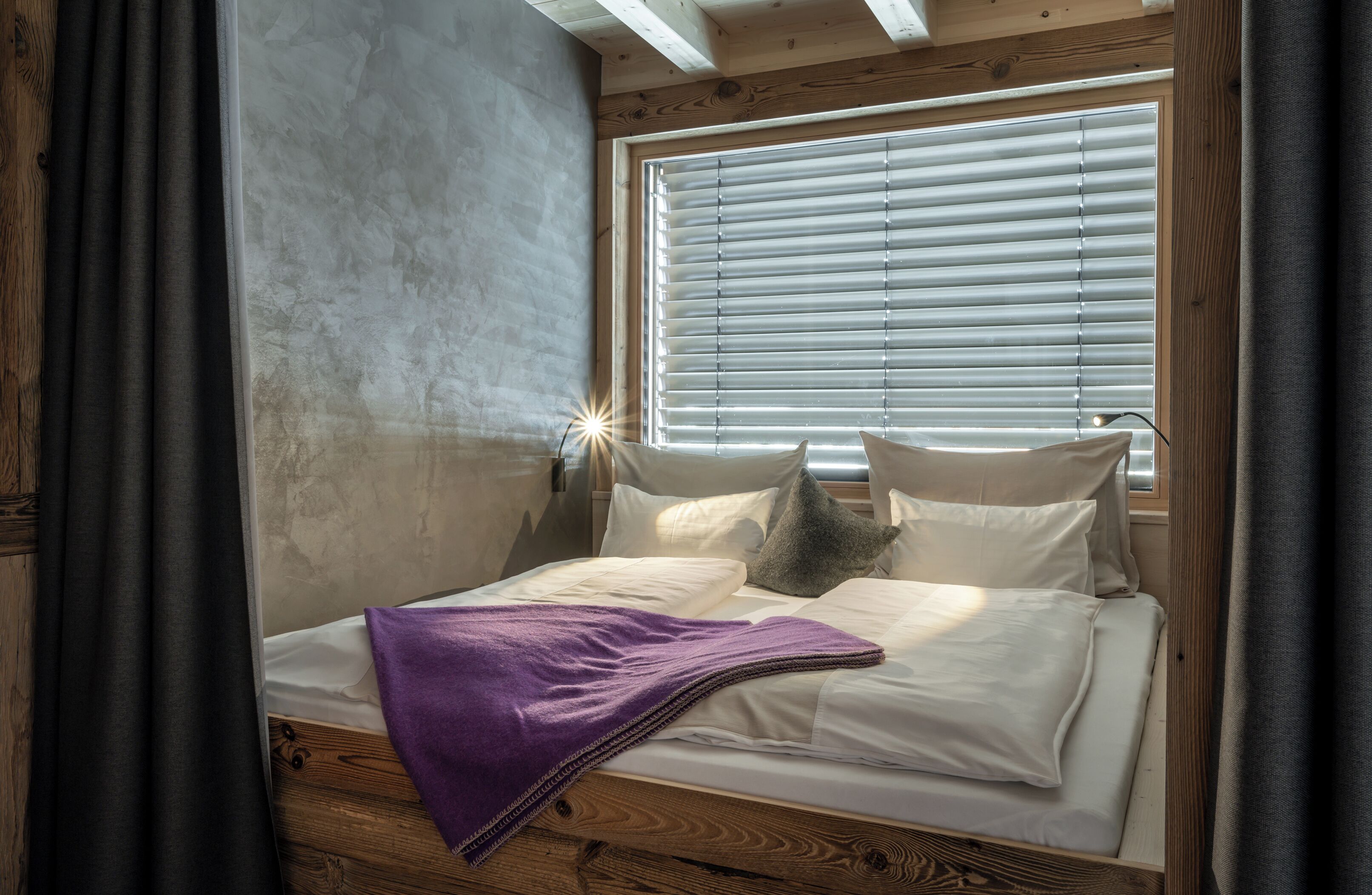 A bed with a purple blanket, white pillows, and a wooden headboard.