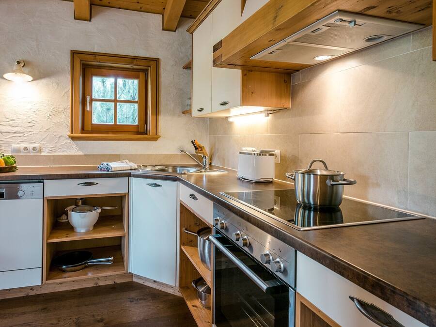 Une cuisine moderne dotée d’appareils électroménagers intégrés, de meubles de rangement en bois et d’une fenêtre offrant une belle vue.