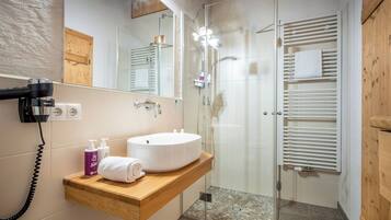 A bathroom with a sink, mirror, towel rack, and shower.
